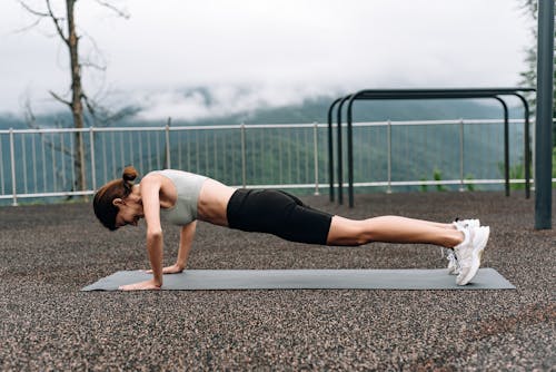 Woman Wearing Activewear Doing Pushups on a Yoga Mat