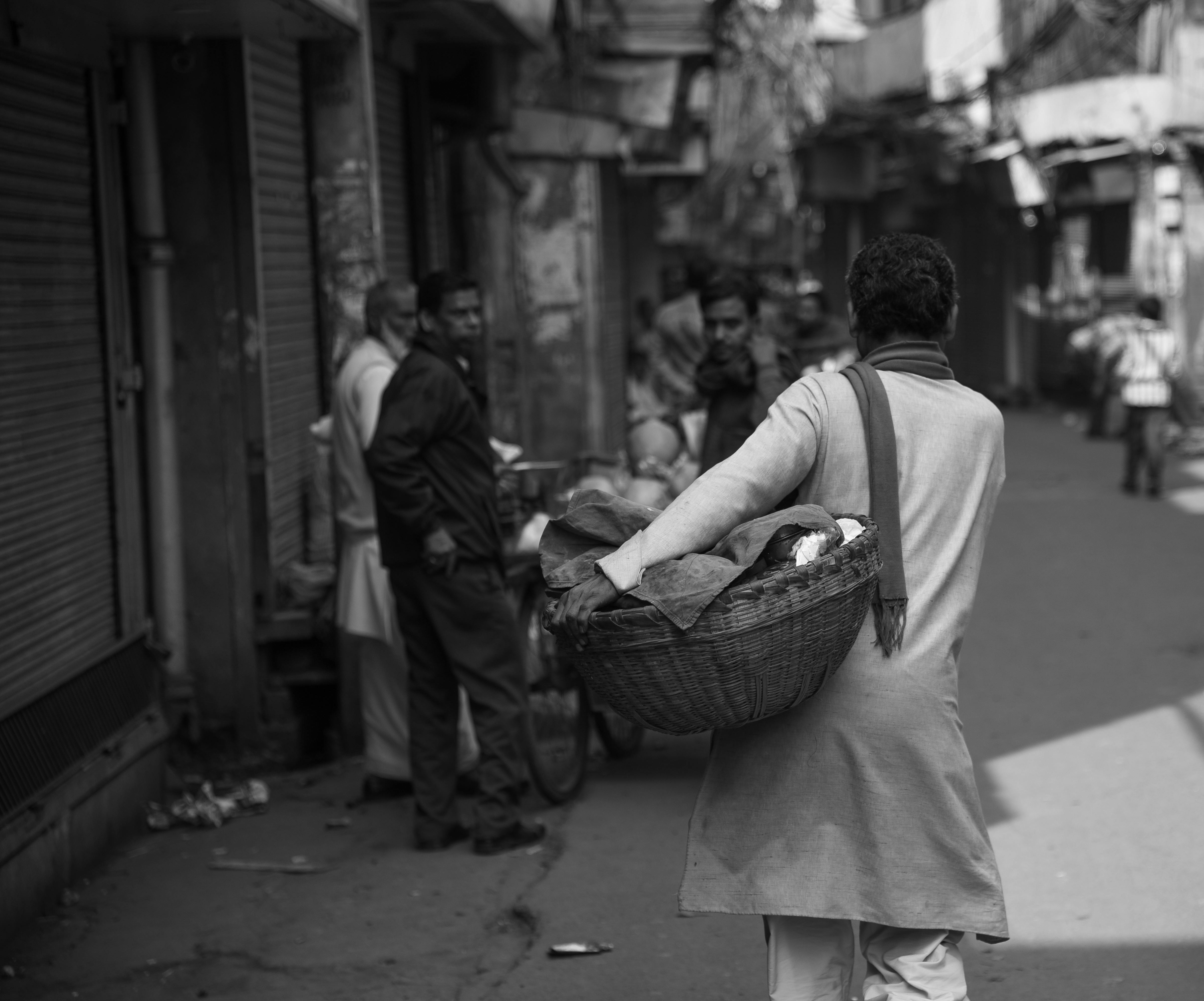 Grayscale Photo of Woman Carrying Basket