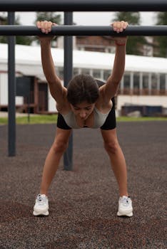 Woman in activewear stretching on monkey bars at an outdoor fitness park, showcasing a healthy lifestyle.