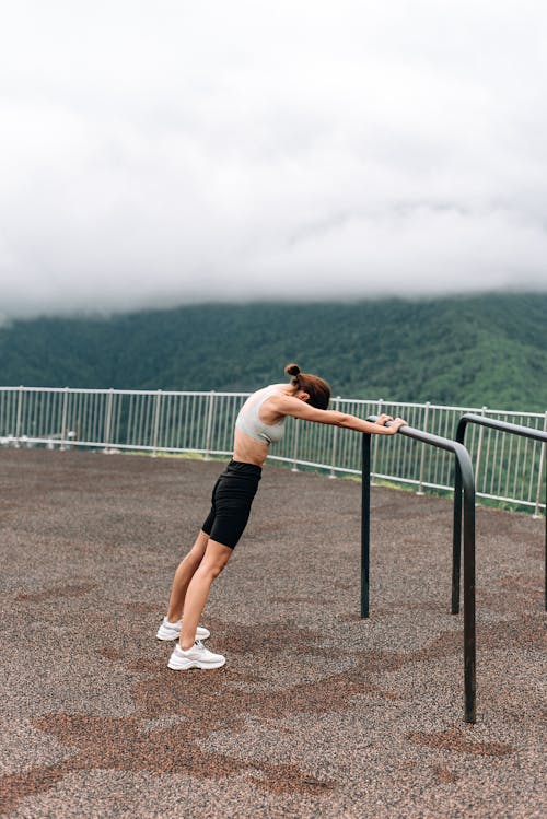 Woman Exercising While Holding on a Bar