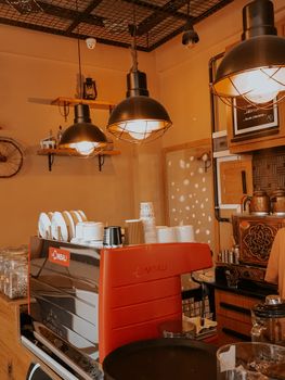 Warm-toned café interior featuring industrial hanging lamps and a coffee counter.