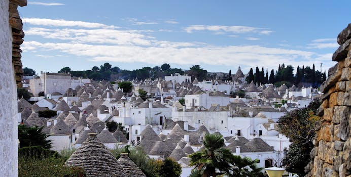 A picturesque view of iconic trulli houses in Alberobello, Italy, under a bright sky.
