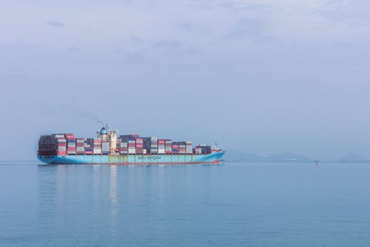 A large cargo ship sails smoothly across the calm ocean near Panama, under a clear blue sky.