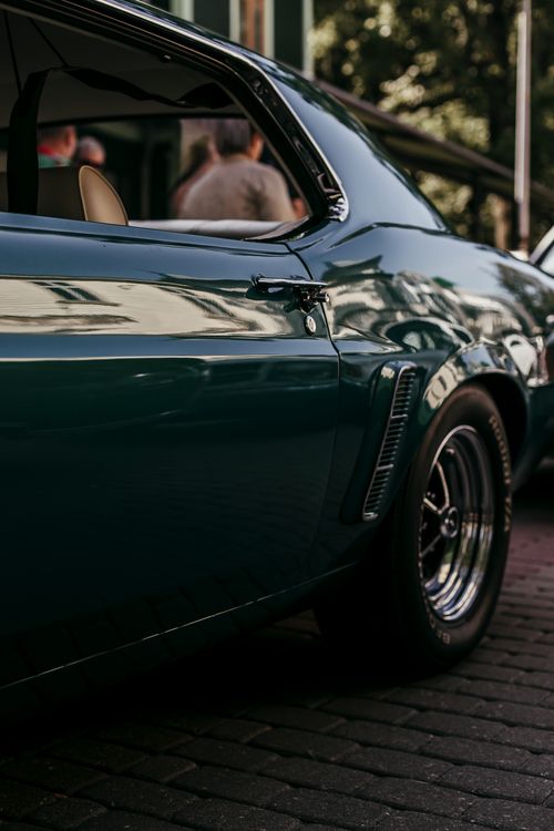 Free Detailed shot of a shiny green muscle car parked at daytime. Stock Photo