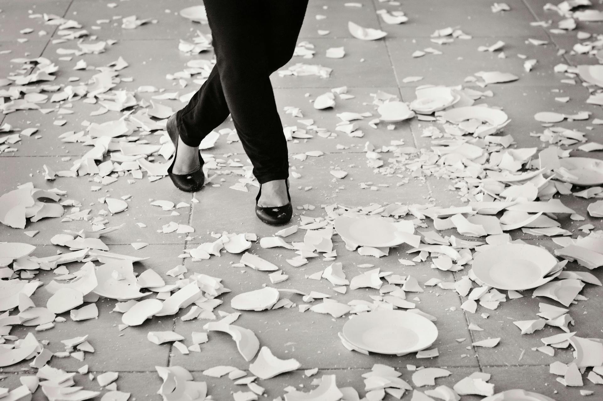 A striking image of broken plates scattered on the floor with a person walking through them.