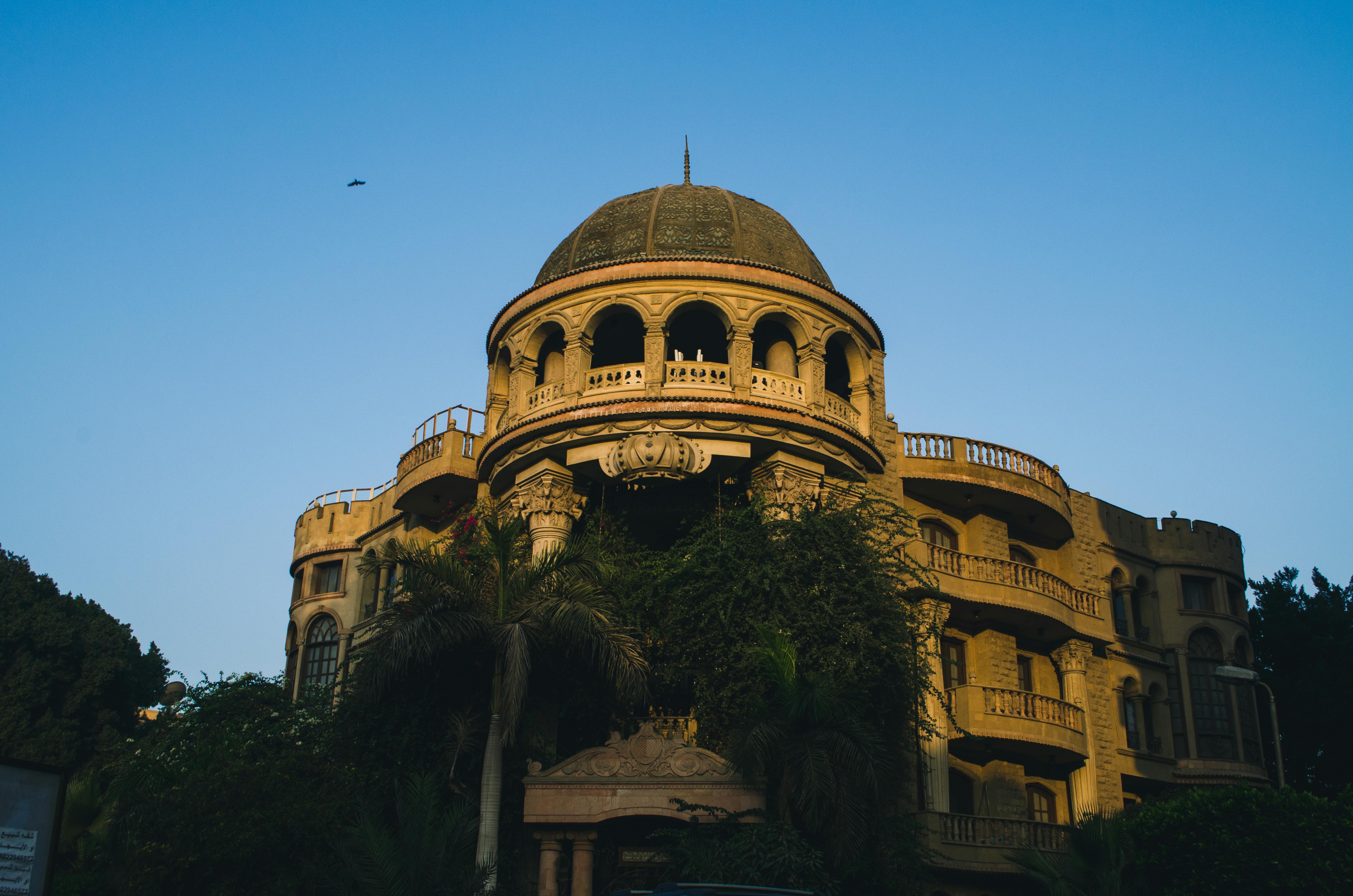 这座令人惊叹的豪宅外观突出一个圆顶，四周环绕着郁郁葱葱的树木，拍摄于黄昏时分