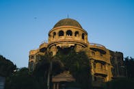 这座令人惊叹的豪宅外观突出一个圆顶，四周环绕着郁郁葱葱的树木，拍摄于黄昏时分