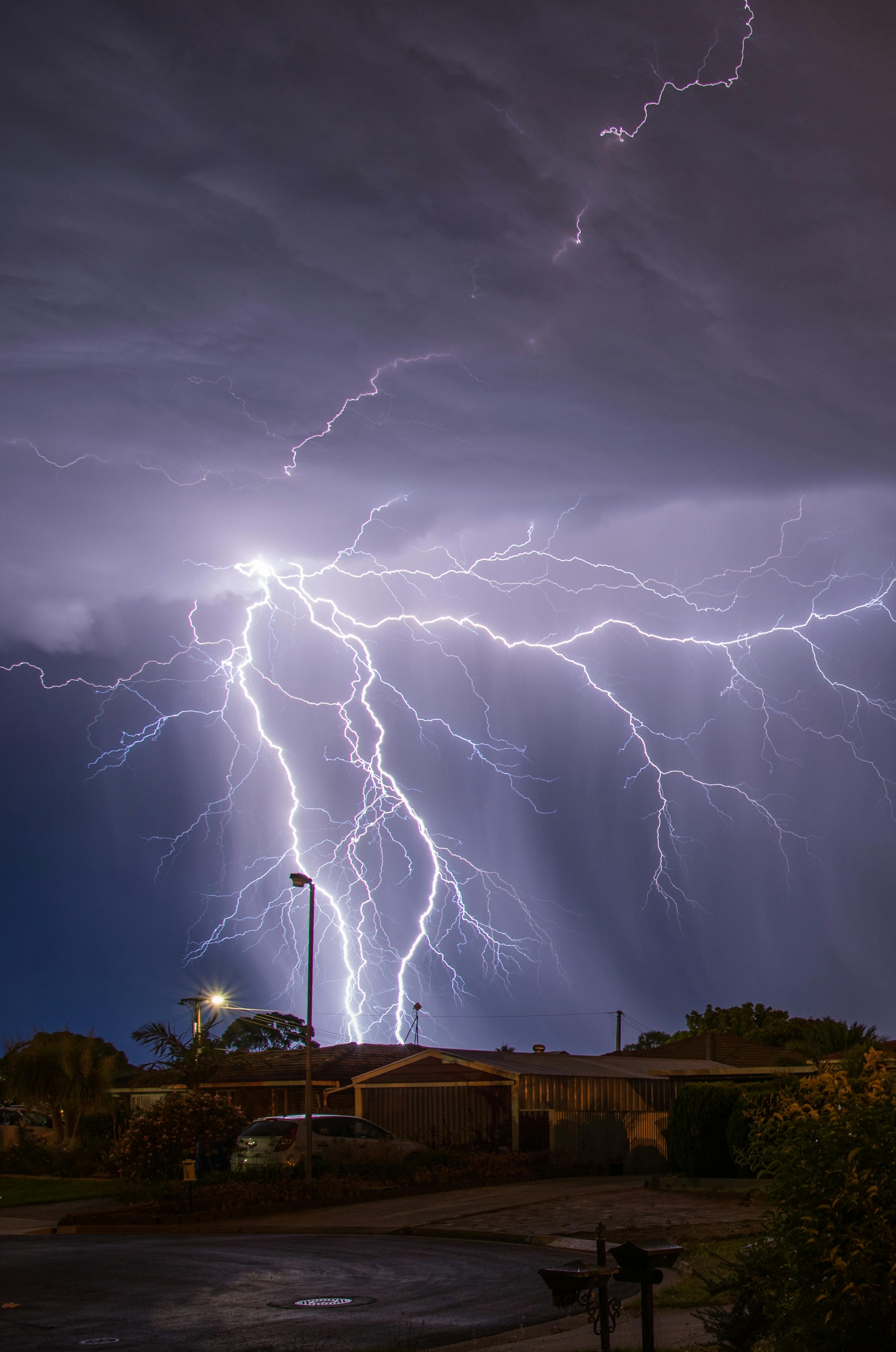 Captivating lightning storm illuminating suburban neighborhood at night.