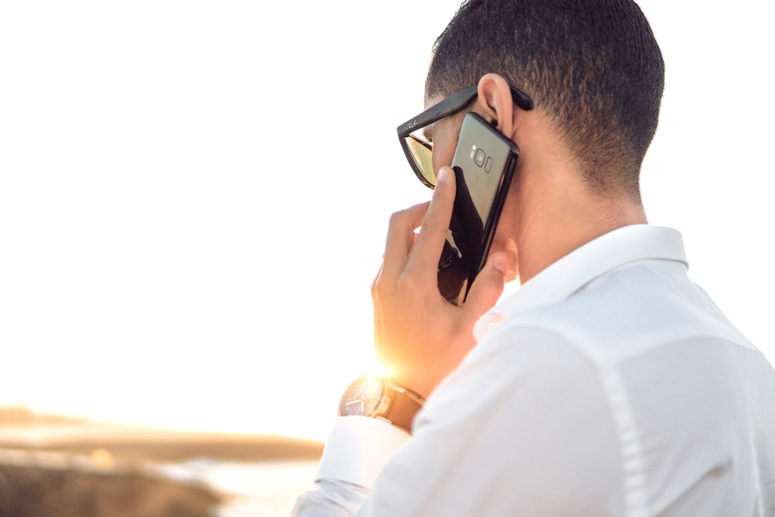 Free Shallow Focus Photography of a Man in White Collared Dress Shirt Talking to the Phone Using Black Android Smartphone Stock Photo