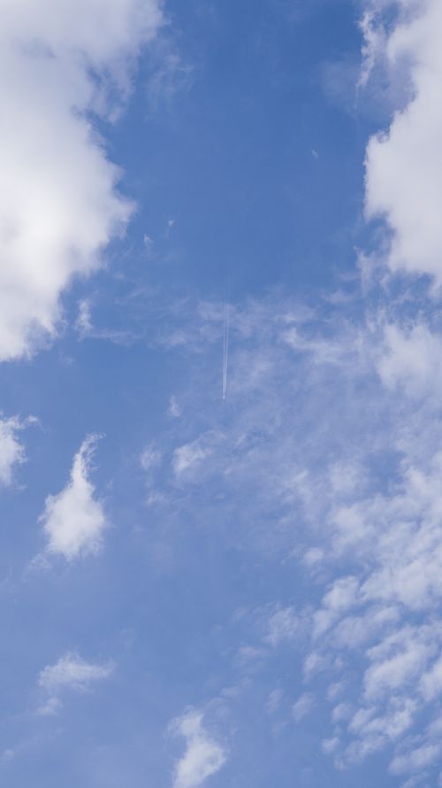 Free A serene skyscape featuring scattered clouds and a visible jet stream against a clear blue sky. Stock Photo