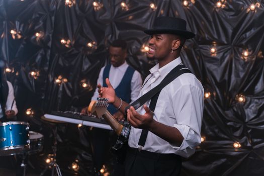 A stylish jazz band performing with guitars and piano, captured indoors with moody lighting.