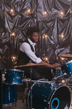 A dynamic drummer playing a drum set with vibrant lighting in an indoor setting.