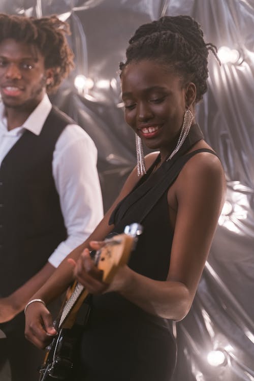 Free Woman in Black Dress Playing the Guitar Stock Photo