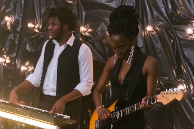 Woman Playing Electric Guitar And Man Playing The Piano