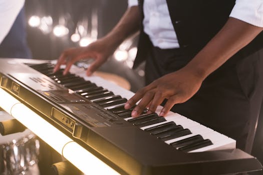 Close-up of musician's hands playing an electronic keyboard in a dimly lit setting.