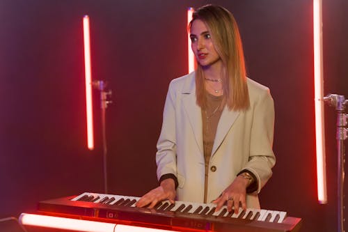 Free Beautiful Woman in White Coat Playing the Piano Stock Photo