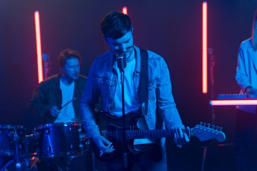 A band performing live on stage with neon lights and electric guitars.