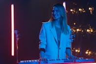 穿着西装外套的女人在舞台灯光下弹奏键盘，散发着欢乐和自信