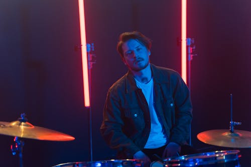 Free Man in Black Jacket Sitting in front of a Drum Set Stock Photo