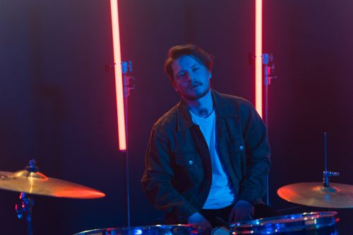 Free Young male drummer playing drums in a neon-lit room, creating a vibrant musical scene. Stock Photo