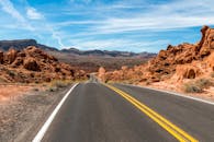 蜿蜒的道路穿过壮丽的沙漠景观，天空蔚蓝，岩石耸立