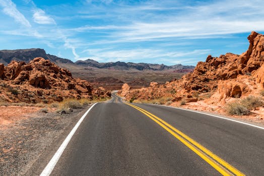 蜿蜒的道路穿过壮丽的沙漠景观，天空蔚蓝，岩石耸立