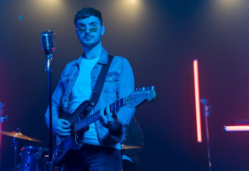 Caucasian guitarist with electric guitar performing live on stage with neon lights.