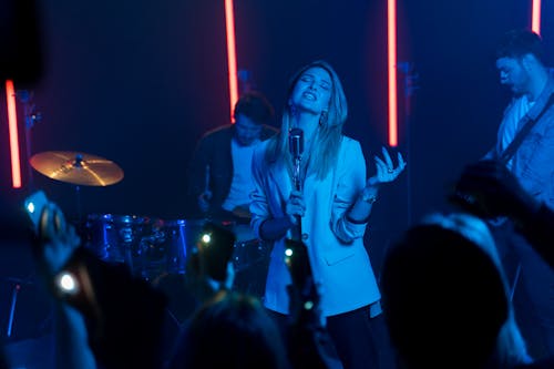 A Woman in White Blazer Singing with Her Eyes Closed