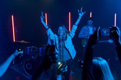 Free Energetic band performing live on stage with vibrant lighting and enthusiastic crowd capturing moments. Stock Photo