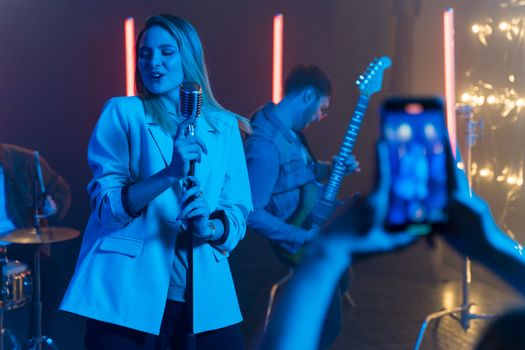 Dynamic live music performance featuring a female singer and guitarist on stage with vibrant lighting.