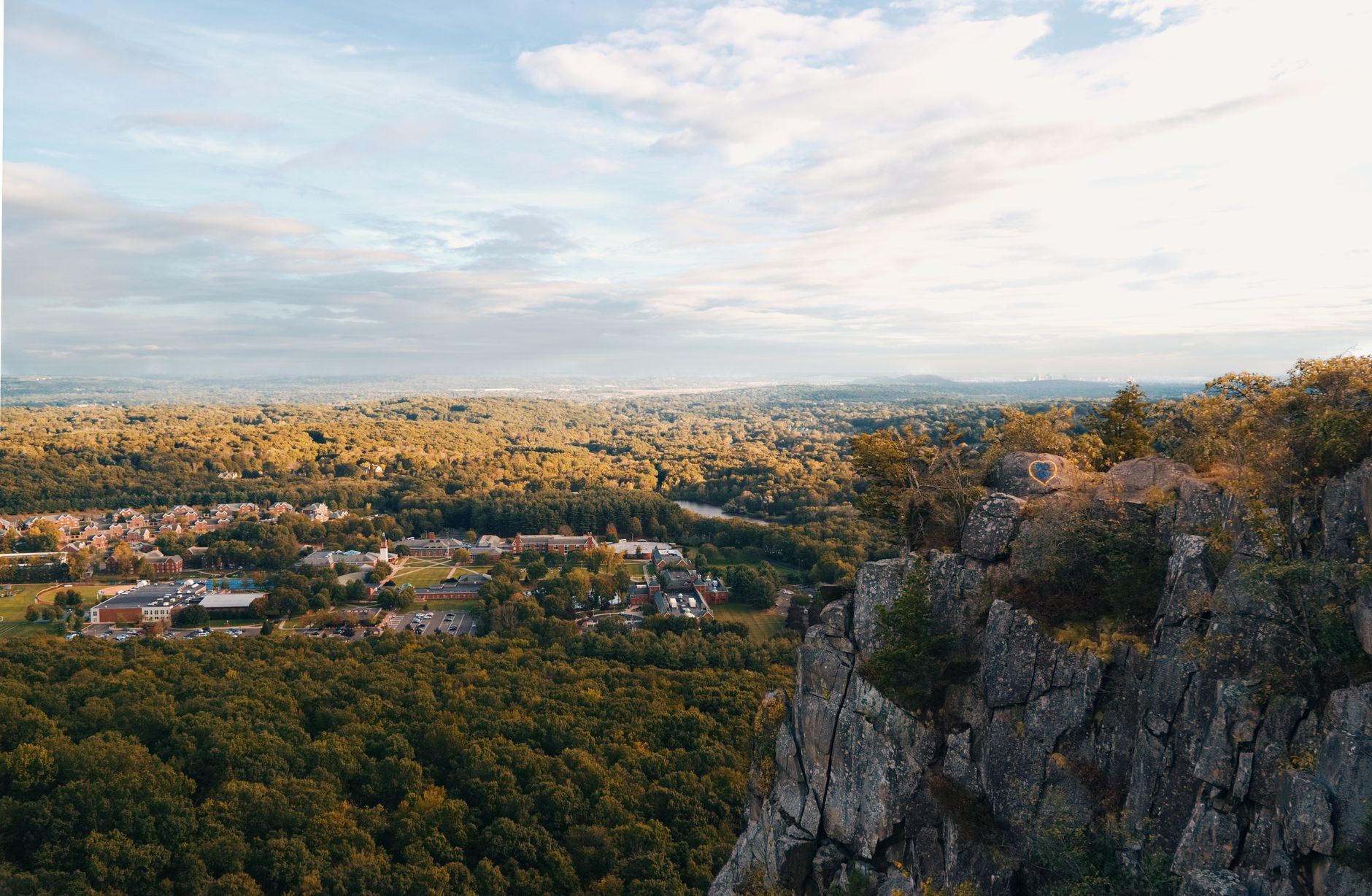 Breathtaking aerial view of Hamden's cliffside overlooking lush forests and distant town.