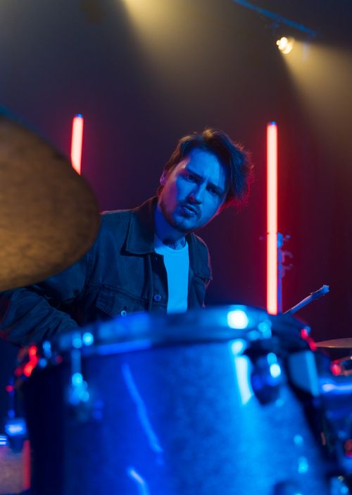 Free Energetic drummer playing on stage with dramatic lighting and neon backlights. Stock Photo