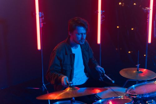 Free A passionate drummer playing in a vibrant neon-lit setting, captured in a dynamic moment. Stock Photo