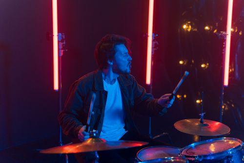 Free A dynamic drummer performing energetically amidst colorful stage lights, creating a vibrant nightlife atmosphere. Stock Photo