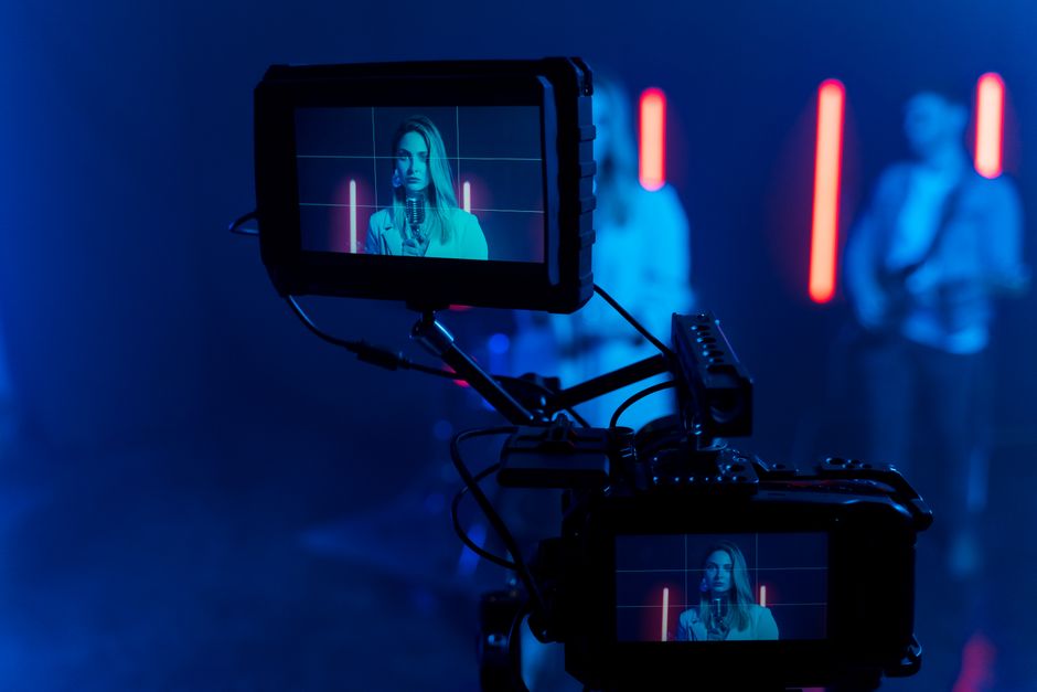 Close-up of a woman singing during a music video shoot with a focus on the camera screen.