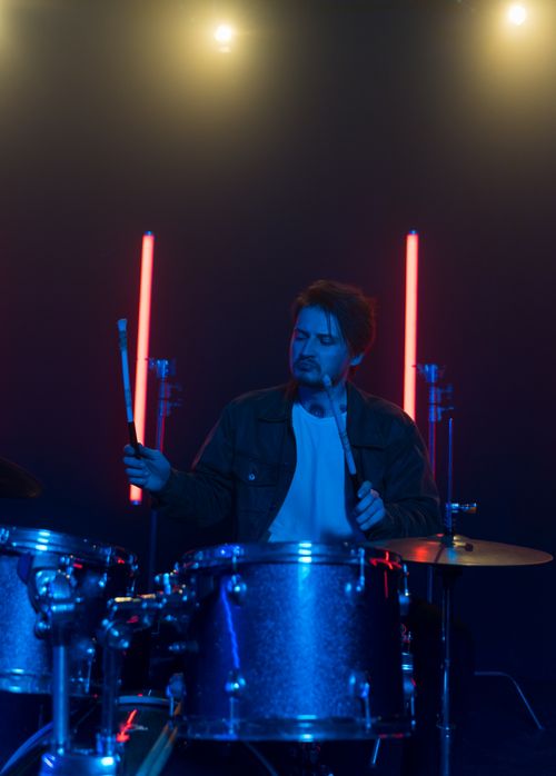 Free A drummer performing energetically on stage surrounded by colorful neon lights. Stock Photo