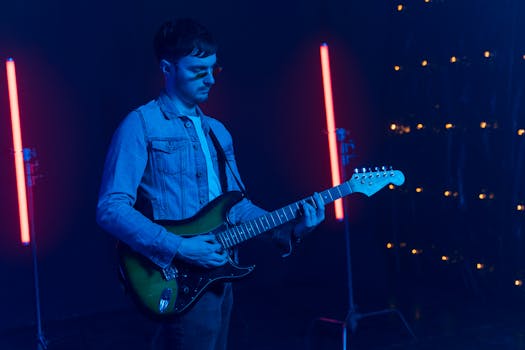 Musician playing electric guitar in a vibrant setting with neon blue and red lighting.