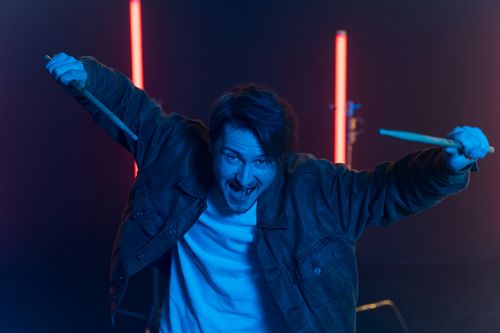 Free Dynamic portrait of a drummer holding sticks with vibrant neon lighting. Stock Photo