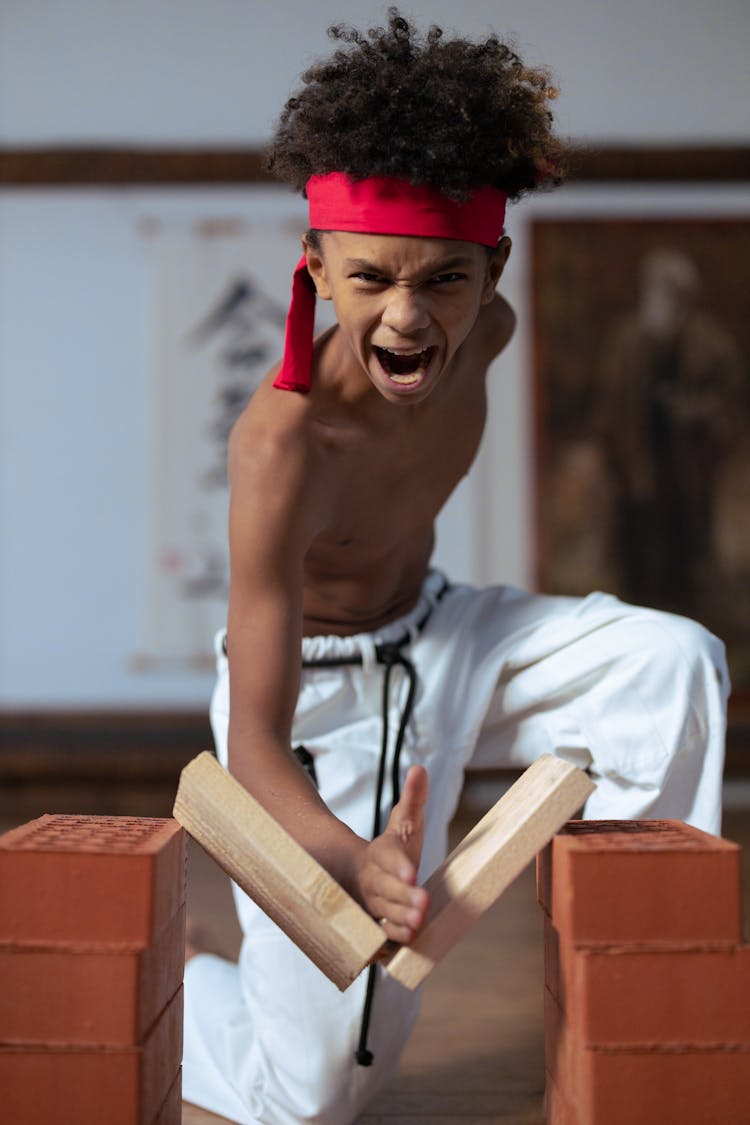 A Boy Breaking A Board In Martial Arts