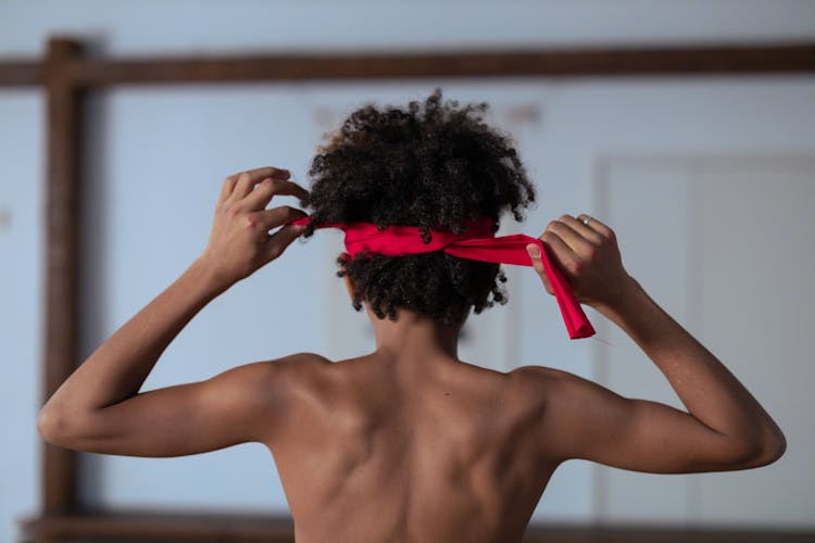 Shirtless Boy Tying Red Headband