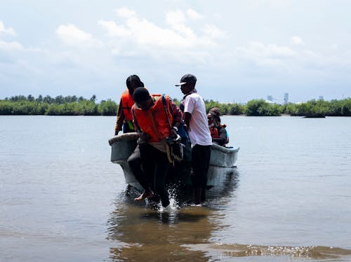 People Pulling a Boat on the Seashore