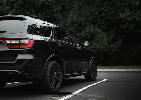 A sleek black SUV parked in an outdoor lot with lush greenery in the background.