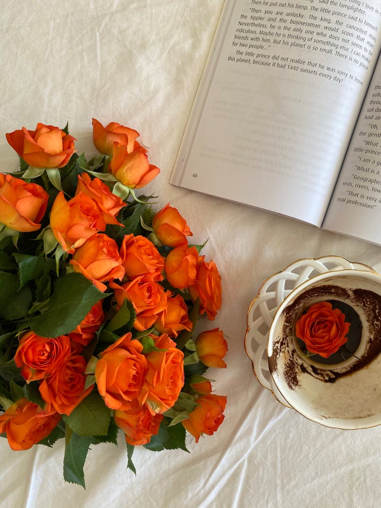 Bouquet Of Red Roses Near An Open Book And A Cup