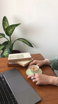 A serene workspace featuring coffee, a laptop, and books on a wooden desk, ideal for productivity.