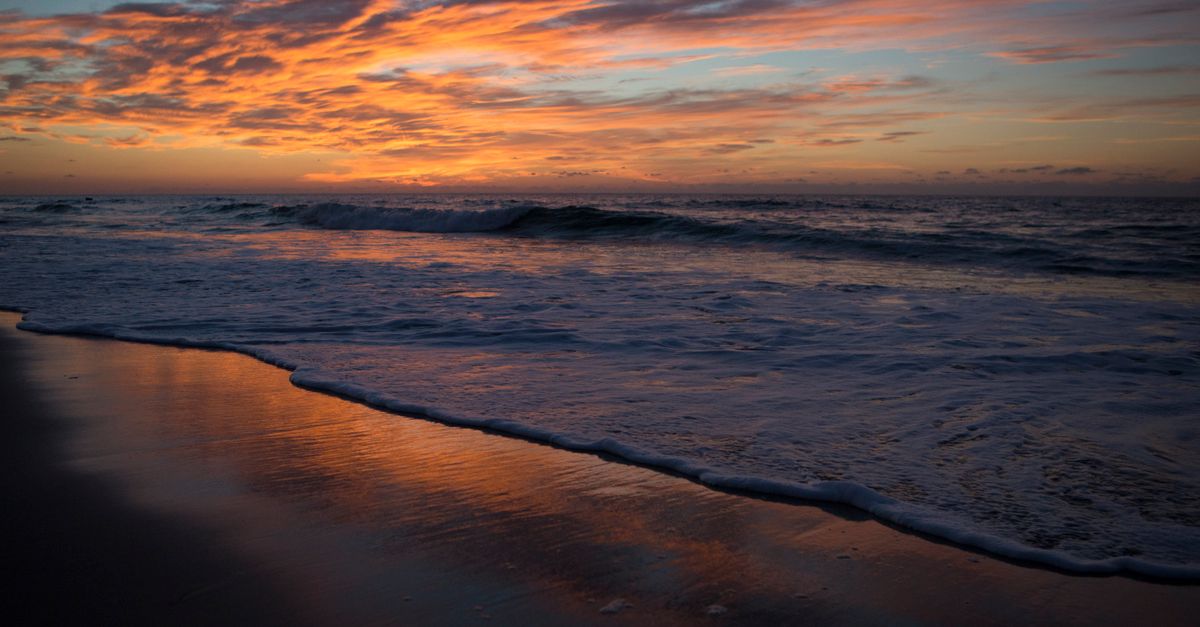 A breathtaking sunrise over Hatteras Island beach with vibrant colors reflecting on the water.