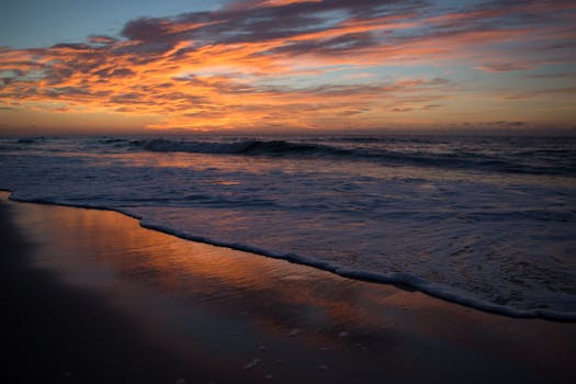 A breathtaking sunrise over Hatteras Island beach with vibrant colors reflecting on the water.