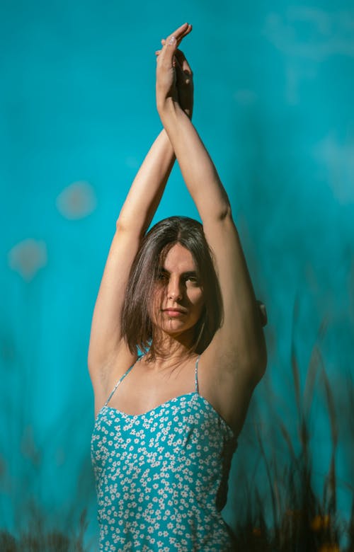 Woman in Blue Floral Top Raising Her Both Arms