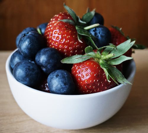 Close-Up Photo of Nutritious Strawberries and Blueberries in White Ceramic Bowl