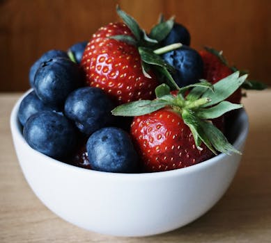 Close-up of fresh strawberries and blueberries in a ceramic bowl, showcasing their vibrant colors and healthy appeal.