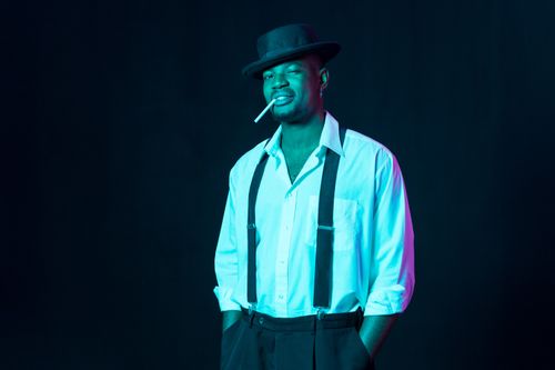 Free Confident man wearing suspenders and black hat with cigarette against a dark background. Stock Photo